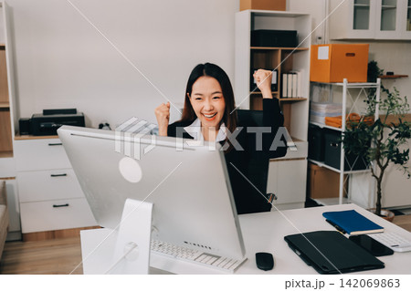 Asian businesswoman using calculator and working on laptop at modern office 142069863