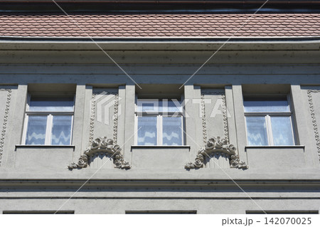 Ornate building facade with windows and decorative reliefs 142070025