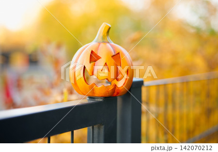 Halloween pumpkin lantern placed on metal fence outdoors. Halloween pumpkin lantern placed on metal fence outdoors. 142070212