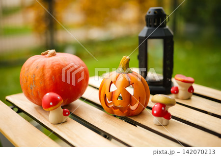 Autumn pumpkins and mushrooms with lantern displayed on wooden table outdoors. Autumn pumpkins and mushrooms with lantern displayed on wooden table outdoors. 142070213