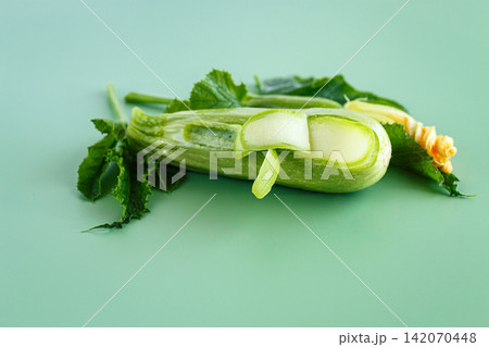 Young green zucchini prepared with thin vegetable ribbons on green background Young green zucchini prepared with thin vegetable ribbons on green background 142070448