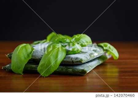 Frozen basil portions prepared for storage on brown wooden background Frozen basil portions prepared for storage on brown wooden background 142070460