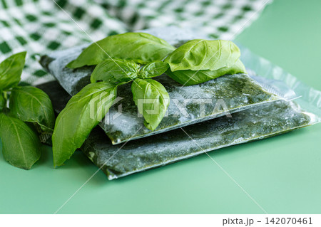 Vacuum sealed basil portions for freezer storage on soft green background Vacuum sealed basil portions for freezer storage on soft green background 142070461