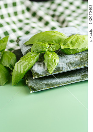 Basil preserved by freezing in vacuum bags with green leaves Basil preserved by freezing in vacuum bags with green leaves 142070462