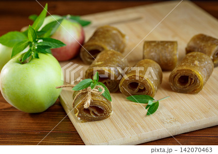 Homemade apple fruit leather rolls with fresh green apple on wooden background Homemade apple fruit leather rolls with fresh green apple on wooden background 142070463
