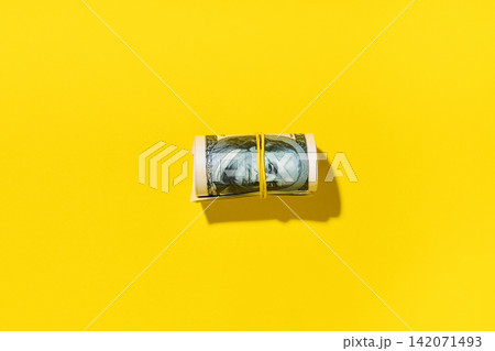Roll of hundred dollar bills on yellow background Roll of hundred dollar bills on yellow background 142071493