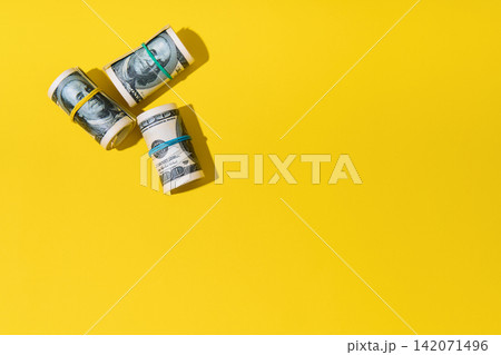 Rolls of hundred dollar bills on yellow background Rolls of hundred dollar bills on yellow background 142071496