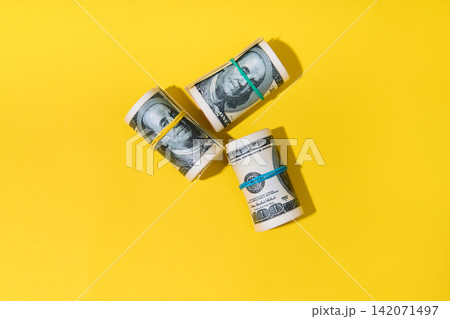 Rolls of hundred dollar bills on yellow Rolls of hundred dollar bills on yellow 142071497