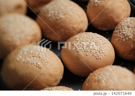 many baked sesame topping burger breads lay on oven tray waiting for cooking, shot with shallow focusing  for using as background wallpaper 142071640