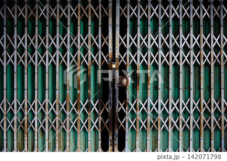 Steel door with bars that locked with small steel chain and gold lock Steel door with bars that locked with small steel chain and gold lock 142071798