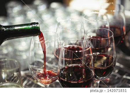 pouring wine in many glasses for dinner party, shot with narrow focus. 142071831