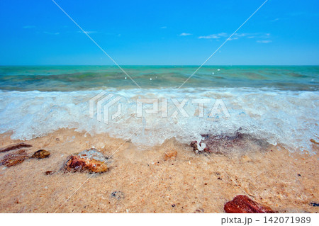 blue sea wave on the yellow sand with white bubbles blue sea wave on the yellow sand with white bubbles 142071989