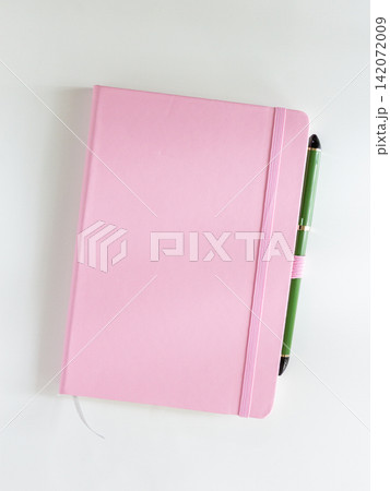 Pink notebook with green pen tucked in elastic band, top view Pink notebook with green pen tucked in elastic band, top view 142072009