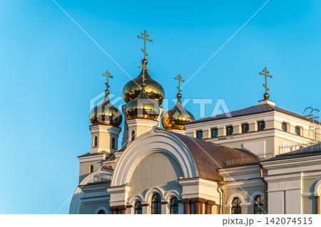 Gilded dome with a cross of an Orthodox church against a blue clear sky Gilded dome with a cross of an Orthodox church against a blue clear sky 142074515
