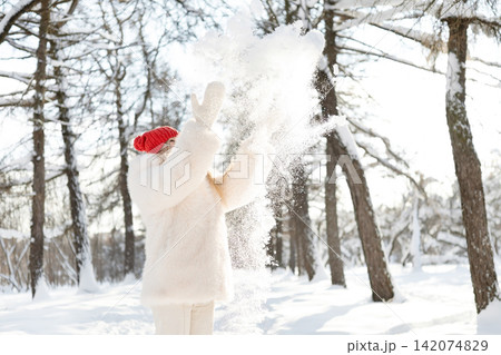 Woman throwing snow in winter forest Woman throwing snow in winter forest 142074829