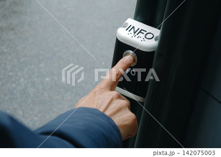 a man presses an outdoor public information button 142075003