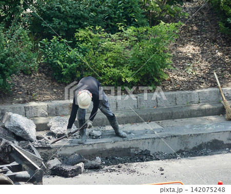 夏の昼の都市の街の道路工事現場で働く作業員の姿 夏の昼の都市の街の道路工事現場で働く作業員の姿 142075248