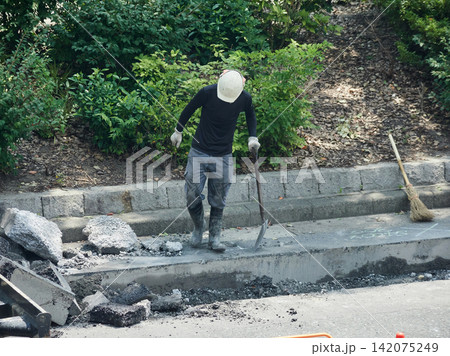 夏の昼の都市の街の道路工事現場で働く作業員の姿 夏の昼の都市の街の道路工事現場で働く作業員の姿 142075249