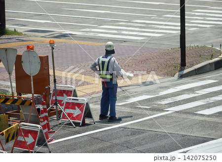 夏の昼の都市の街の道路工事現場で働く中年男性警備員の姿	 142075250