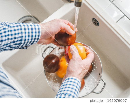Male hands wash ripe tomatoes 142076097