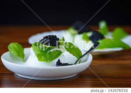 Gourmet egg with black caviar on rustic wooden background Gourmet egg with black caviar on rustic wooden background 142076558