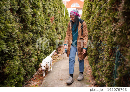 Young adult woman walking a dog on a path Young adult woman walking a dog on a path 142076768