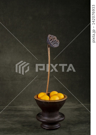 Dried lotus in a vase with marbles on a green background Dried lotus in a vase with marbles on a green background 142076933