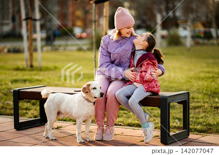 Mother and daughter bonding with pet dog in park Mother and daughter bonding with pet dog in park 142077047