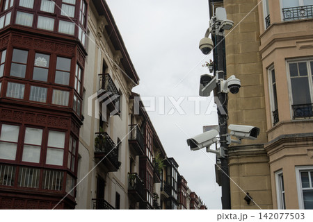 Security cameras on a pole between old apartment buildings in a city centre 142077503