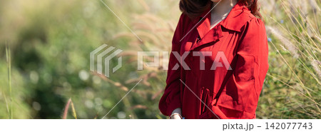 woman in a vibrant red dress standing in a sunny mission grass field. 142077743