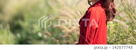 woman wearing a red dress walking through a tall grass field. woman wearing a red dress walking through a tall grass field. 142077748