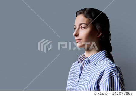 Thoughtful young female student looking away against studio background 142077865