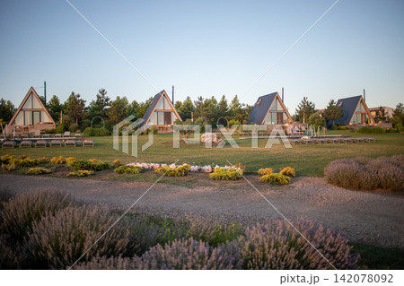 Scenic landscaped park with colorful flower beds, ornamental grasses and houses in the distance, capturing peaceful suburban greenery, garden design and warm evening sunlight outdoors Scenic landscaped park with colorful flower beds, ornamental grasses and houses in the distance, capturing peaceful suburban greenery, garden design and warm evening sunlight outdoors 142078092