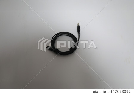 Black USB charging cable neatly coiled on a clean white background, creating a minimal technology composition for electronics, connectivity, power supply and digital accessory concepts Black USB charging cable neatly coiled on a clean white background, creating a minimal technology composition for electronics, connectivity, power supply and digital accessory concepts 142078097