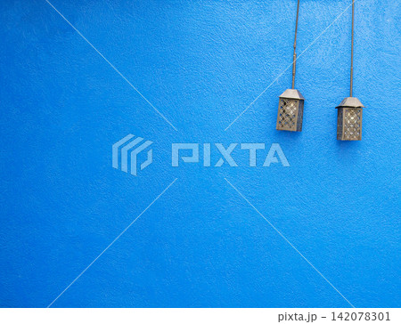 Blue wall texture background with vintage hanging lanterns Blue wall texture background with vintage hanging lanterns 142078301