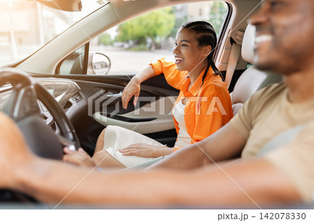 Young Black woman smiling in passenger seat beside her partner inside car Young Black woman smiling in passenger seat beside her partner inside car 142078330
