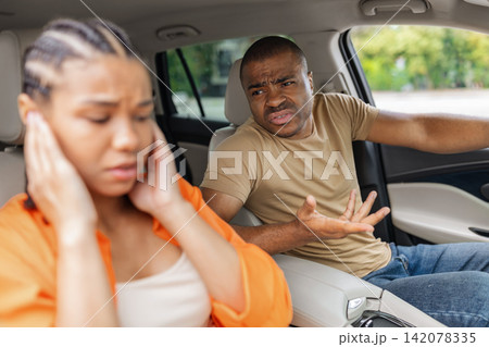 Young African American couple arguing inside car, frustrated man gesturing angrily Young African American couple arguing inside car, frustrated man gesturing angrily 142078335