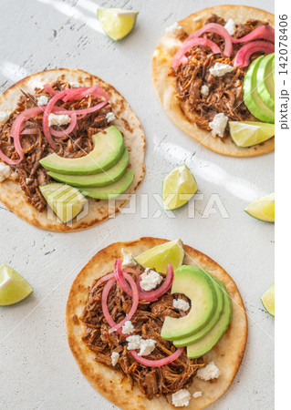 Open faced pulled beef tacos with avocado pickled onions queso fresco lime Open faced pulled beef tacos with avocado pickled onions queso fresco lime 142078406