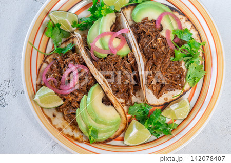 Pulled beef tacos with avocado pickled onions cilantro lime Mexican street food Pulled beef tacos with avocado pickled onions cilantro lime Mexican street food 142078407