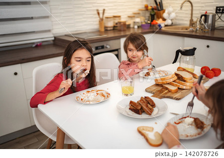 Children eating breakfast in kitchen, enjoying family meal time 142078726