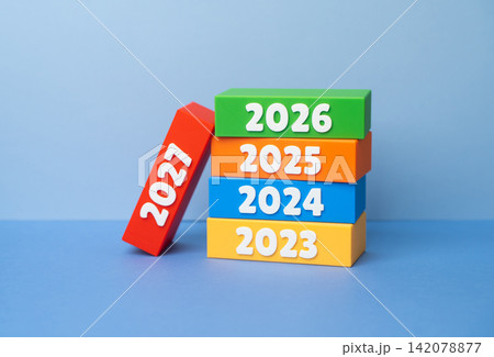 A stack of dominoes with the years 2027. Preparing for the New Year, making plans and setting goals. Strategic vision, goal setting, new beginnings, economic forecasts A stack of dominoes with the years 2027. Preparing for the New Year, making plans and setting goals. Strategic vision, goal setting, new beginnings, economic forecasts 142078877