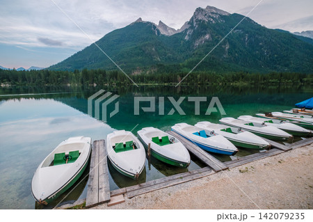 Row of pedal boats at Hintersee lake with Hoher Goll mountain in Germany Row of pedal boats at Hintersee lake with Hoher Goll mountain in Germany 142079235