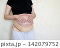 Pregnant woman showing love and connection with her unborn baby by making a heart shape with her hands on her belly. Maternity support belt, prenatal care, pregnancy health and motherhood concept. 142079752