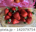 Fresh ripe strawberries in plastic container close up on kitchen table 142079754
