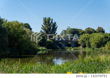 Concrete water dam and small bridge over river surrounded by green trees Concrete water dam and small bridge over river surrounded by green trees 142079791