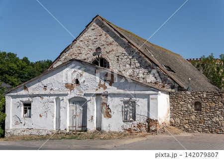 Old abandoned building with weathered plaster facade near stone wall in Ukraine Old abandoned building with weathered plaster facade near stone wall in Ukraine 142079807