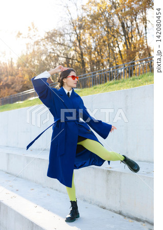 Beautiful woman relaxing at the park near sportground wearing autumn clothing. Young smiling woman confident looking at camera Beautiful woman relaxing at the park near sportground wearing autumn clothing. Young smiling woman confident looking at camera 142080454