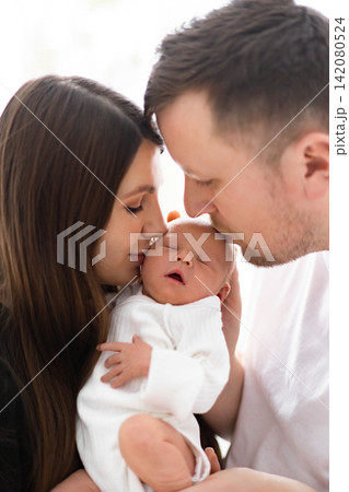 A mother and father tenderly embrace their newborn baby, sharing a moment of pure love and connection 142080524