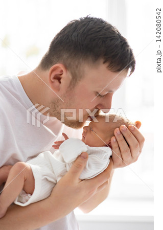 A tender moment captured as a father gently kisses his newborn baby's forehead, showcasing deep love and connection A tender moment captured as a father gently kisses his newborn baby's forehead, showcasing deep love and connection 142080542