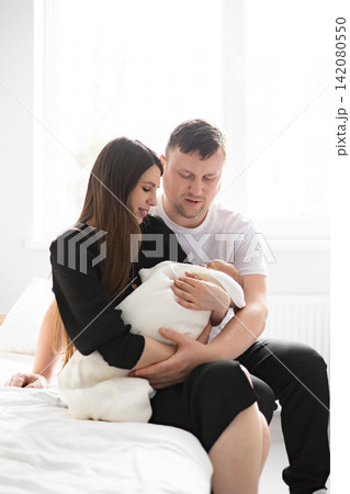 A loving family of three, a mother and father gently holding their newborn baby wrapped in a soft blanket 142080550